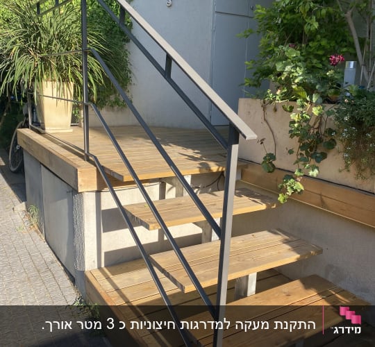 מעקה מתכת שחור על מדרגות עץ חיצוניות